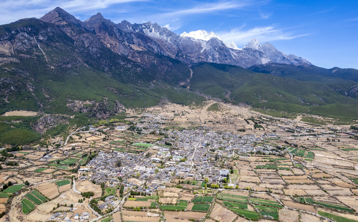 An aerial drone photo taken on March 25, 2024 shows the Yulong Snow Mountain and Yuhu village in Lijiang City, southwest China's Yunnan Province. (Xinhua/Chen Xinbo)